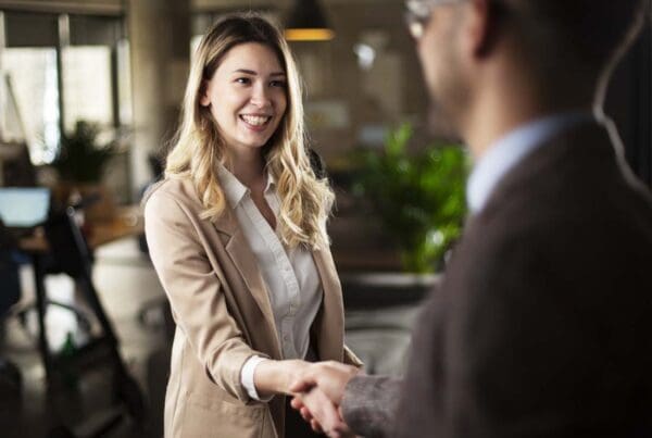 We Are Independent - Businesswoman Shakes Hands and Greets a Client in a Bustling Modern Office
